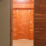 14 out of 15 photographs. The interior of a walk-in, all-cedar closet is shown through a door. The lighting inside the closet gives it a golden glow.